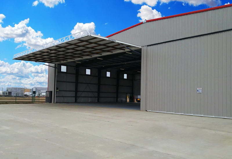Exterior of a prefab steel airplane hangar with door lifted