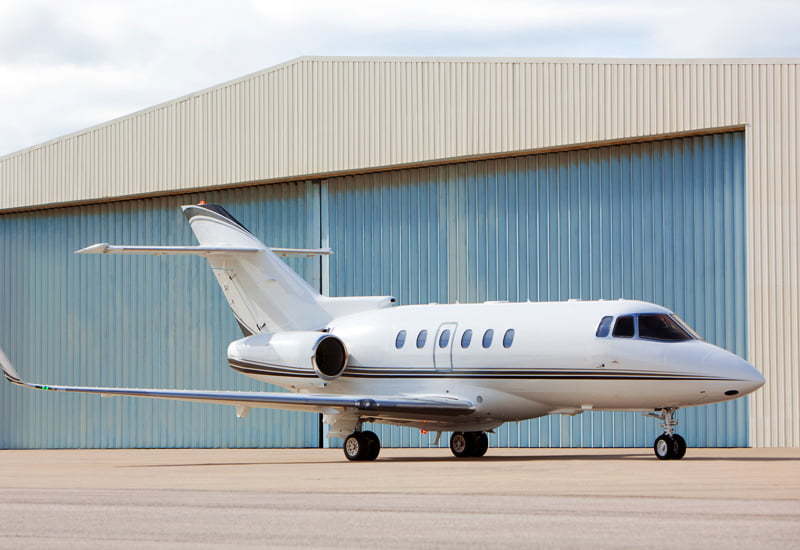 Prefabricated steel airplane hangar with airplane in front and hangar door closed