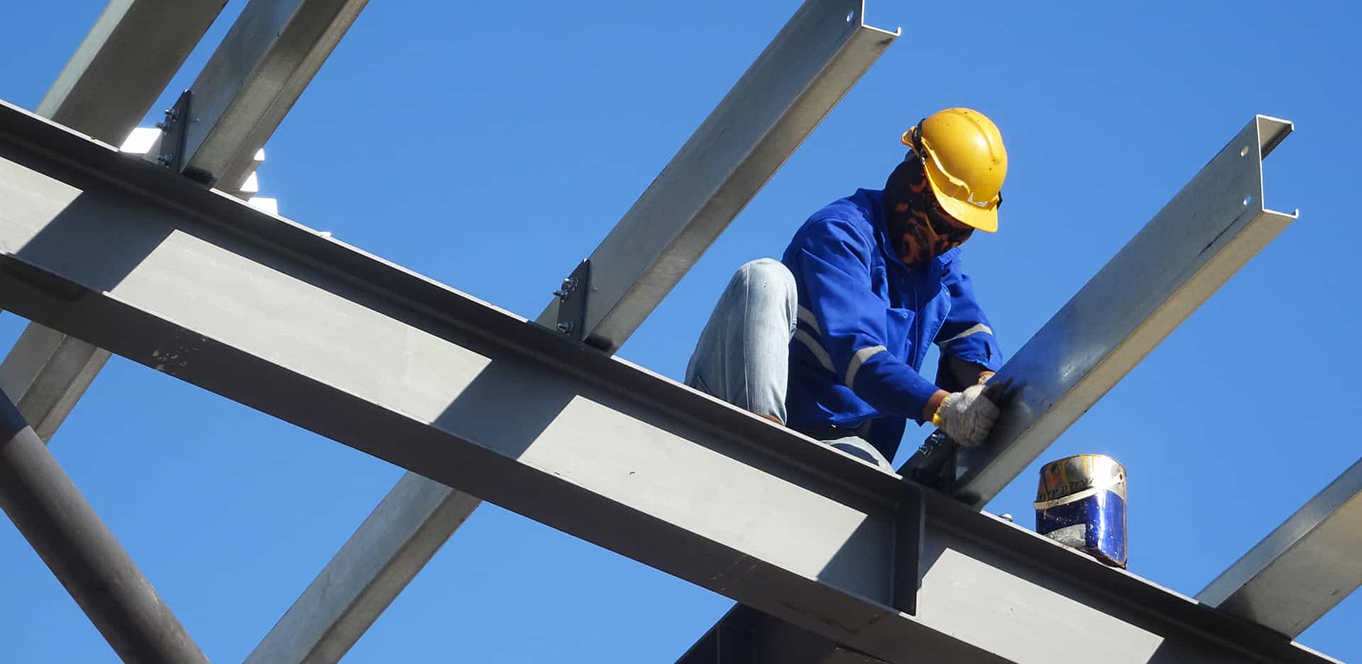 Construction worker installing a steel purlin on a roof